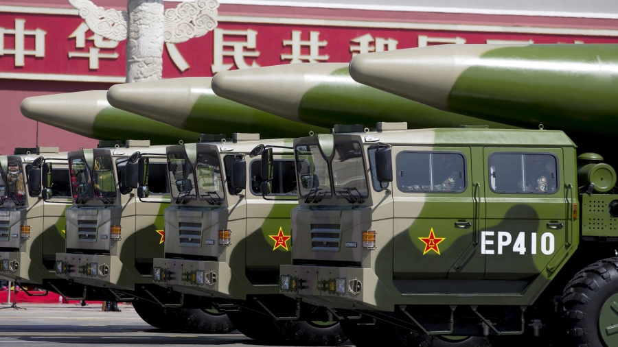Military vehicles carrying DF-26 ballistic missiles travel past Tiananmen Gate during a military parade. Green-colored military vehicles carry DF-26 ballistic missiles.