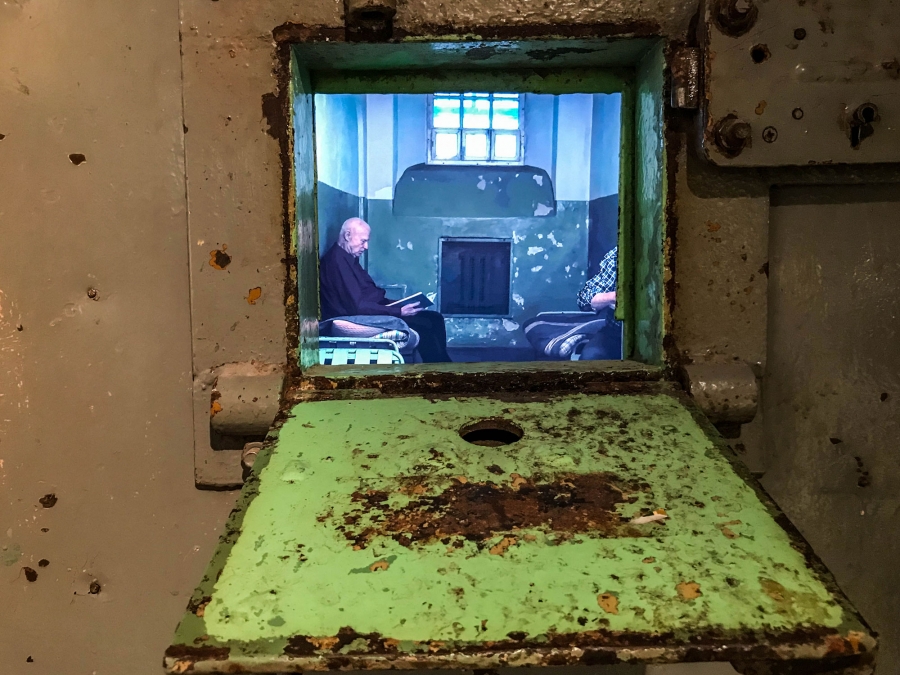 The tiny cellblock windows of these Soviet prison doors have been replaced by screens playing video re-enactments of prison life. The tiny cellblock window is shown open from a bottom hinge.