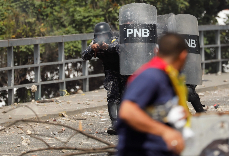 police officers fire bullets behind riot shields