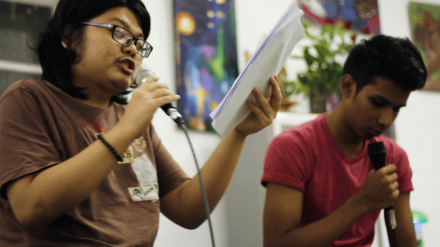 Two young men speak into microphones.