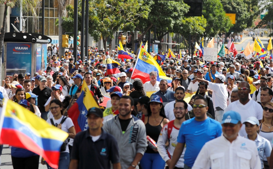 Opposition supporters take part in a rally to commemorate the Day of the Youth and to protest against Venezuelan President Nicolas Maduro's government. Opposition supporters are shown en masse in the street with placards and Venezuelan flags.
