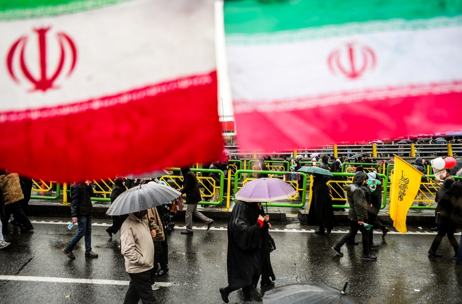 Iranian people carry umbrellas under giant Iranian flags