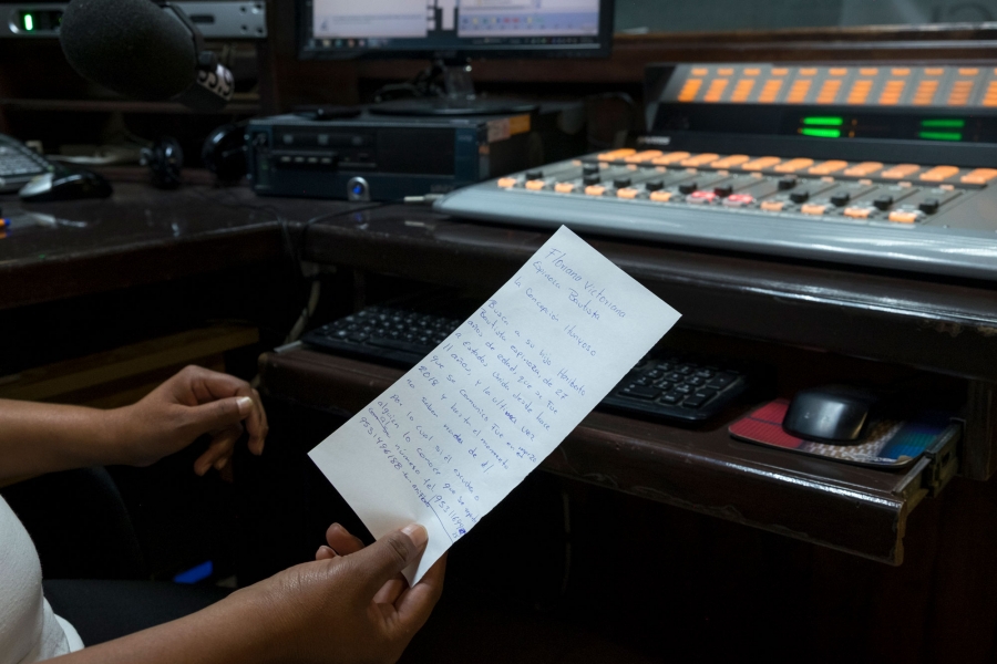 Eva Hernández holds a note written by listener Floriana Espinoza. She writes that she is looking for her 27-year-old son, Heriberto Bautista Espinoza, who left for the US 11 years ago. Espinoza lost communication with him last March. A close-up photo shows Eva Hernández holding a hand-written note by listener Floriana Espinoza.