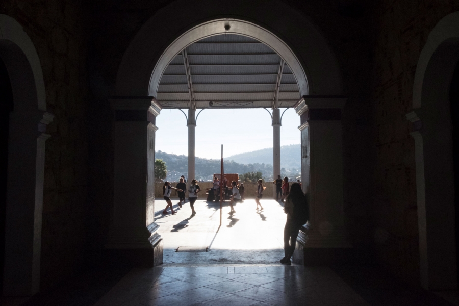 Women play volleyball in a local league at Tlaxiaco’s town hall auditorium. Women are shown playing volleyball in the distance.