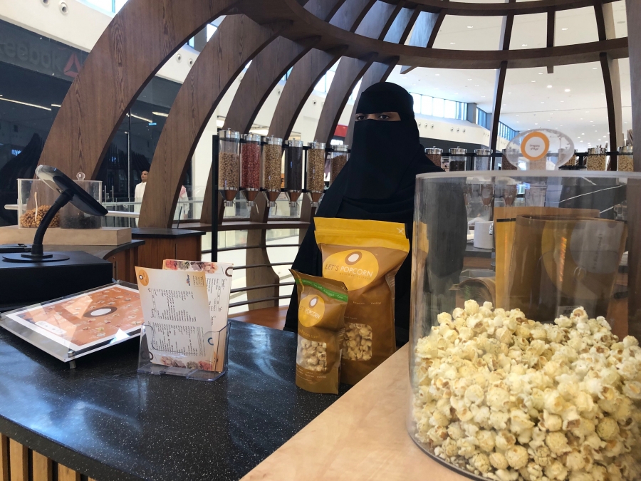 Twenty-five-year-old Hessa sells popcorns at the Riyadh Park mall in Riyadh, Saudi Arabia. A woman wearing a black veil sells popcorn at a stand at a mall.