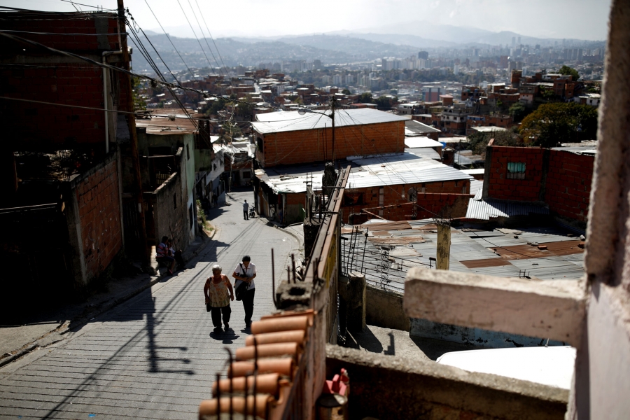 Guzman walks home with her mother-in-law. Two women are shown walking up a hilly street in Caracas.