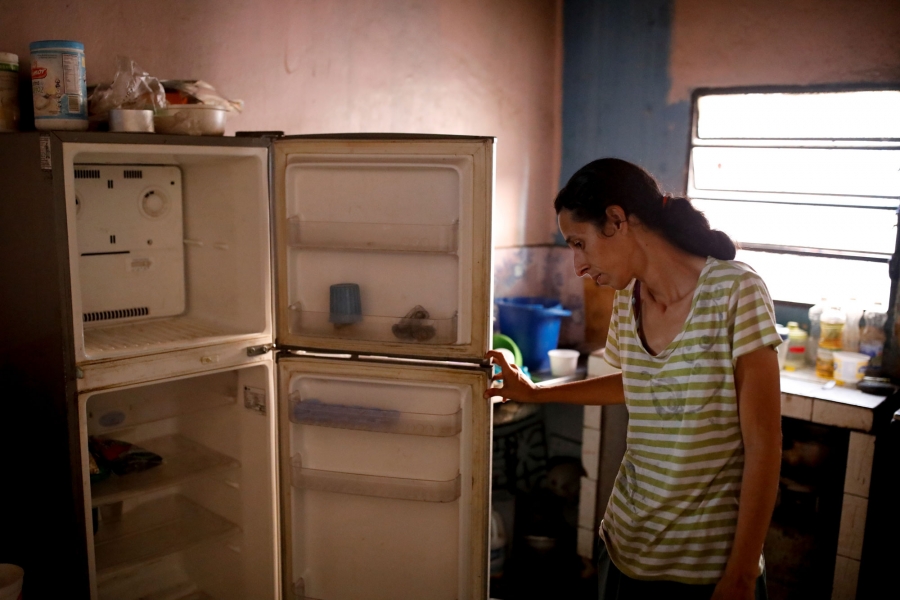 Guzman shows the food she has in her house. A woman is shown standing, opening up her empty refrigerator.