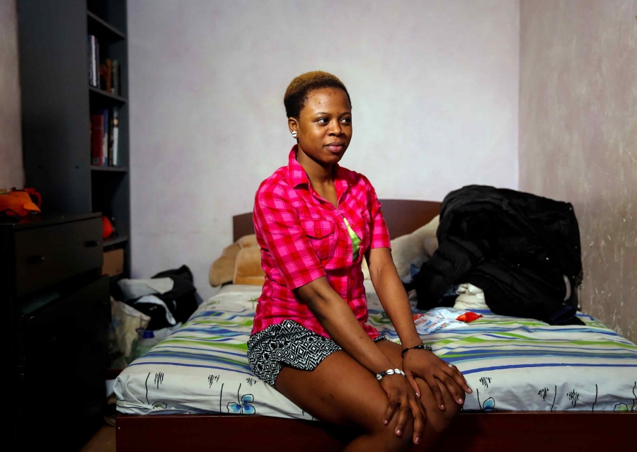 A young woman sits on the edge of bed