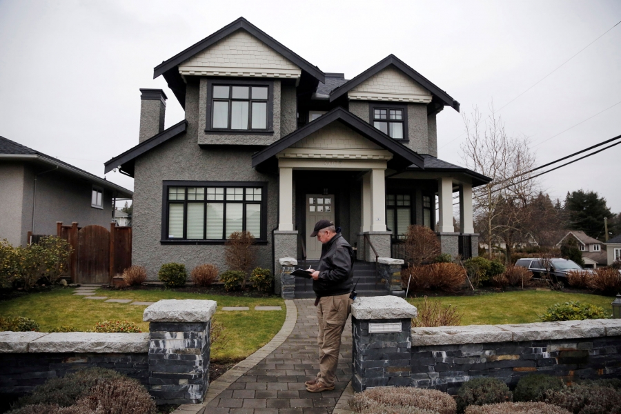 A member of a private security firm stands outside of the family home of Huawei's financial chief Meng Wanzhou, in Vancouver, British Columbia, Jan. 2019. A member of a private security firm is shown stands outside of the family home of Huawei's financial chief Meng Wanzhou with a clipboard and a walkie talkie.