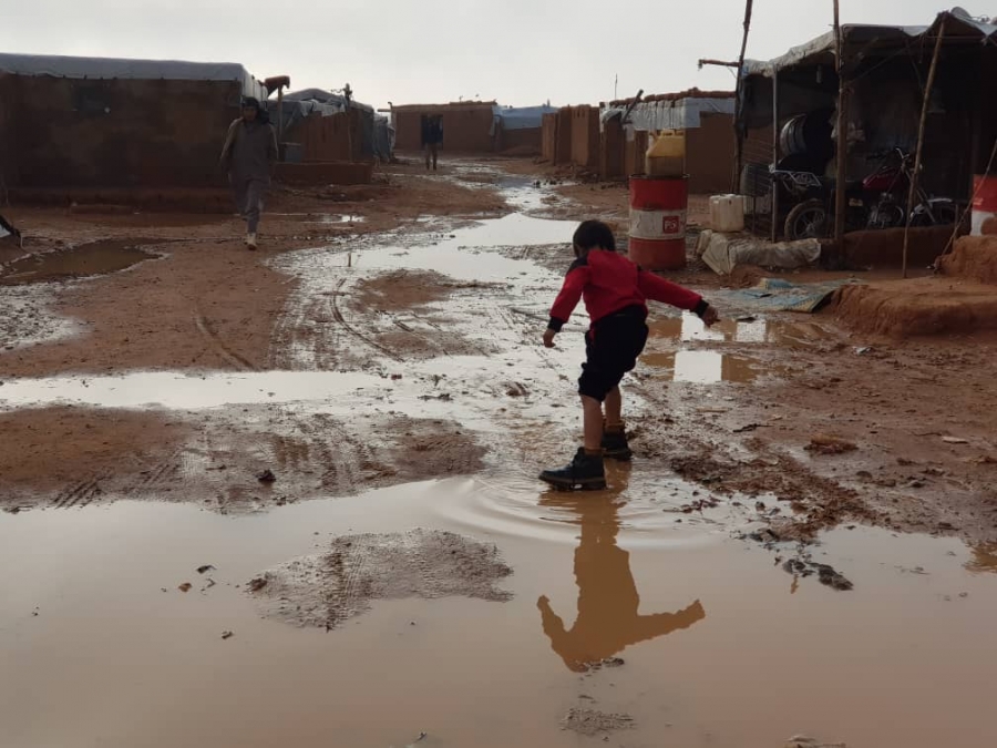 A boy plays in a mud puddle.