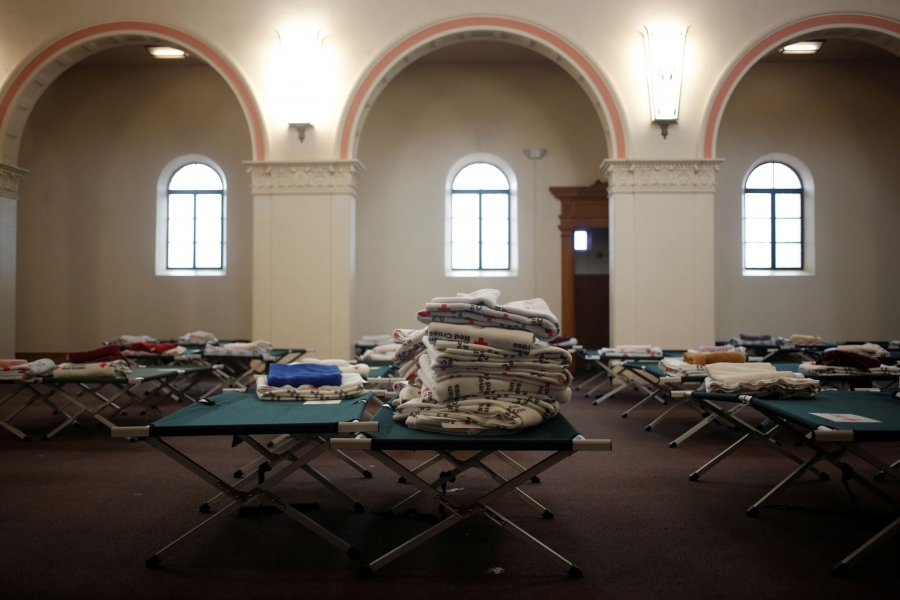Red Cross blankets and cots fill the chapel of the monastery. Stacks of blankets are show sitting on cots in the chapel of the monastery.
