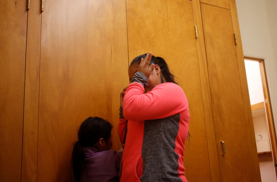 A Guatemalan woman wipes away tears as she talks with family in Guatemala. A Guatemalan woman s shown wearing a pink and grey shirt and wiping away tears.