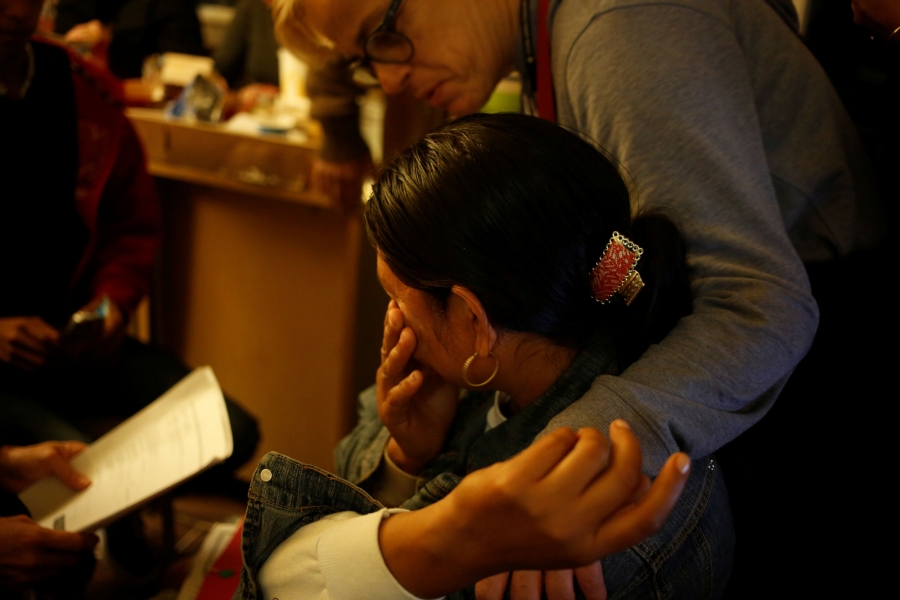 A volunteer comforts a Guatemalan woman after calls to her brother-in-law back in Central America failed to connect. A volunteer is shown comforting a Guatemalan woman show has her hand to her face.
