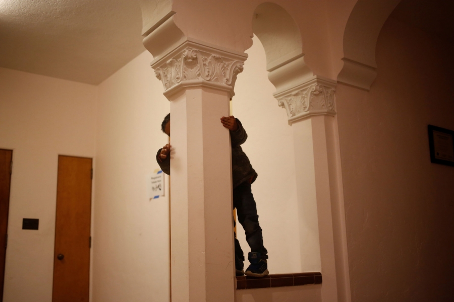 A young Guatemalan boy plays on columns in a monastery. A young Guatemalan boy hides behind an ornate column in a monastery.