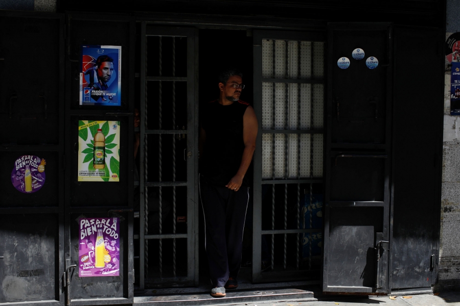 A man walks out a grocery store during an ongoing blackout in Caracas, Venezuela. A man is shown in the door frame of a darkened grocery store.