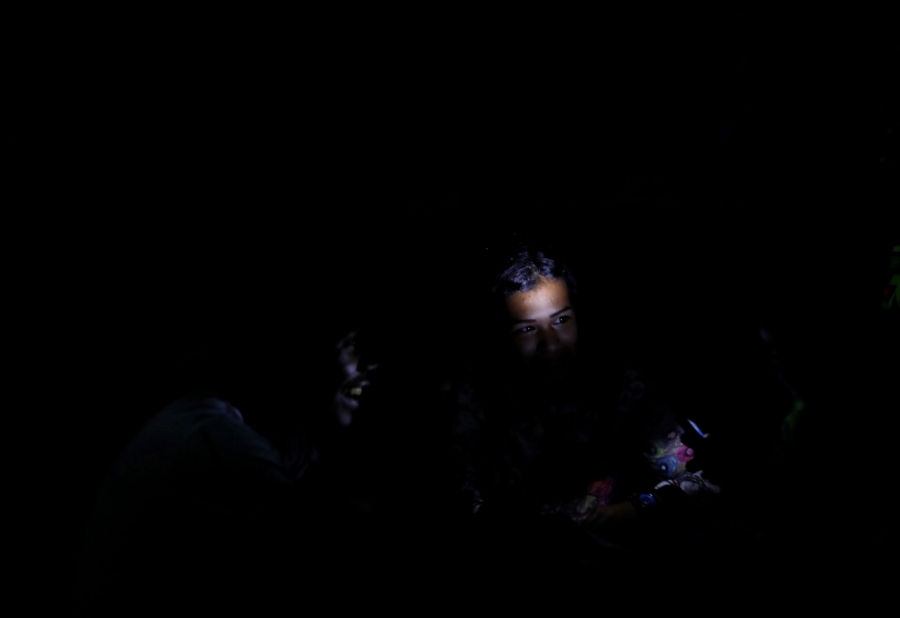 Children play by a cellphone light during the blackout in Caracas, Venezuela. In a nearly all dark photograph, a child's face is illuminated by a cellphone light.