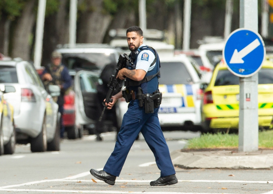 A police officer walks the street following a shooting at the Al Noor mosque in Christchurch, New Zealand. A police, in a short-sleeved uniform and carrying a rifle, is shown walking the street in Christchurch, New Zealand.
