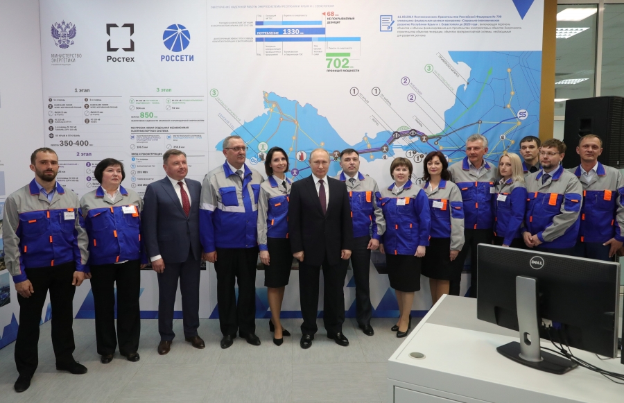 Russian President Vladimir Putin poses with workers