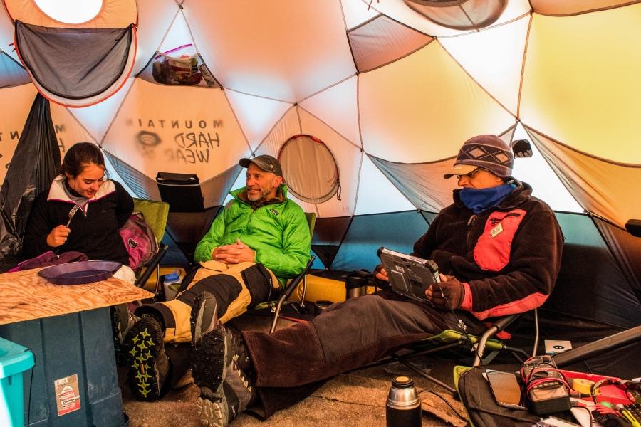 The crew gathered for meals in a tent on the Greenland ice sheet. The crew gathered is shown lounging in chairs for meals in a tent on the ice.