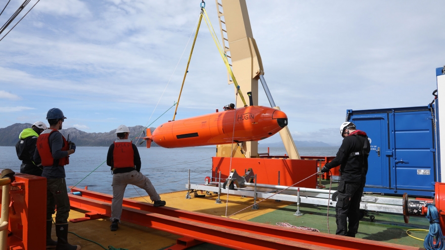 Researchers hoist the Hugin autonomous submarine onto the deck of the Nathaniel B. Palmer at the start of the ship’s mission to study Antarctica’s massive Thwaites Glacier. Researchers hoist the orange-colored Hugin autonomous submarine onto the deck of the Nathaniel B. Palmer.