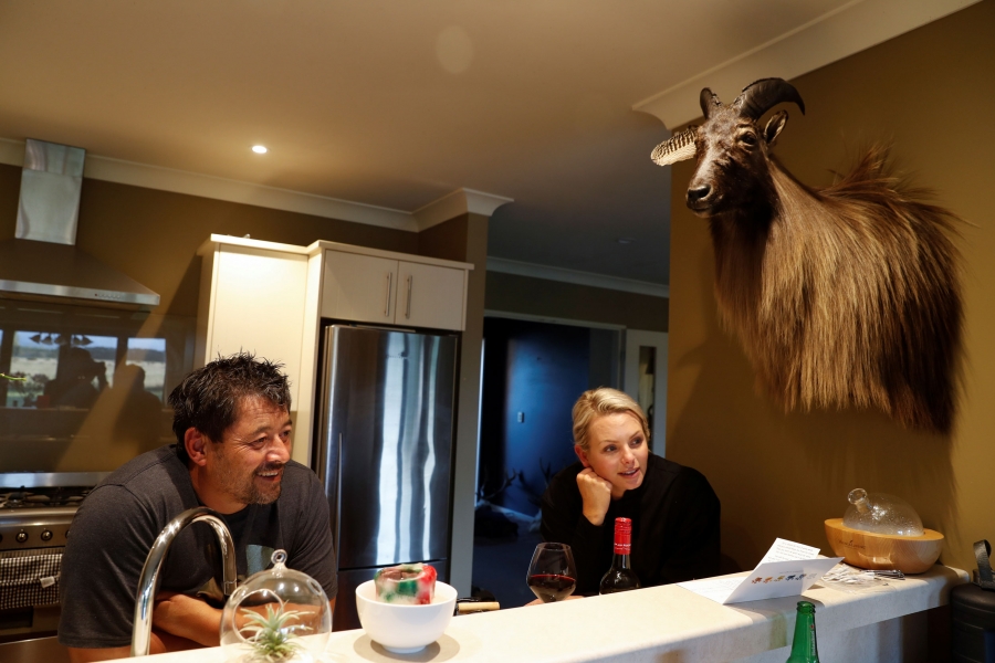 Noel Womersley and his partner Helena chat with a friend at his house outside Christchurch, New Zealand. Noel Womersley and his partner Helena are shown sitting at a kitchen counter chatting with a friend.