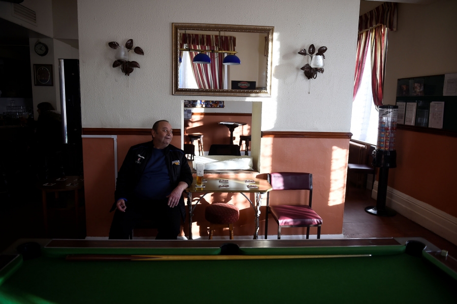 Brown drinks a pint of beer. A man is shown sitting down with a pint of beer behind a billiards table.