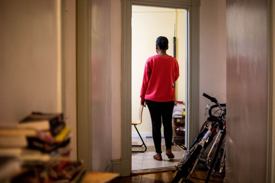 Kettly says her family prays a lot. There's a wooden engraving in their kitchen that reads, "Avec Jésus tout va bien," or "With Jesus, everything will be fine." A woman is show in her kitchen with a red sweatshirt and black pants.