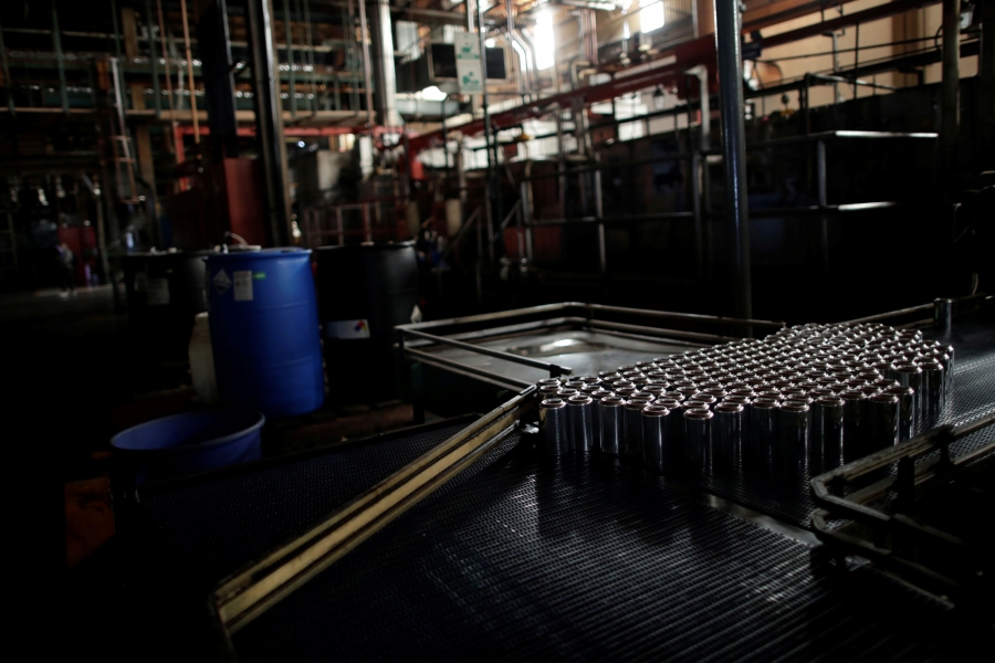 Cans are seen on a halted machine at a factory during a power cut in Valencia, Venezuela. Shiny silver cans are seen on a halted machine in a darked room.