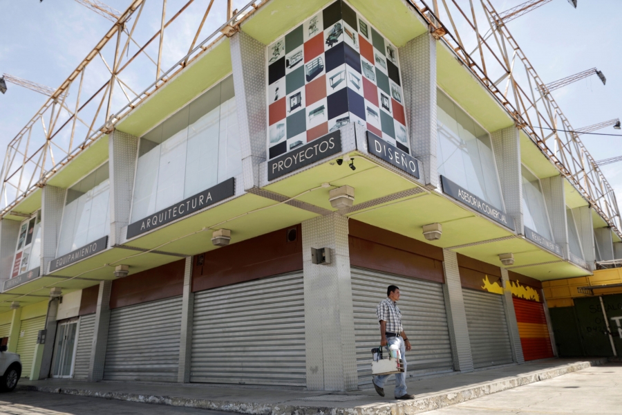 A man walks past closed local shops in Valencia, Venezuela, Venezuela. A man walks past several storefronts that have metal gates pulled down.