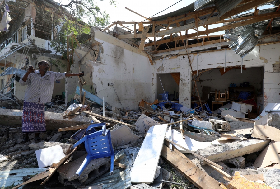 Somali man stands in ruins of rubble. 