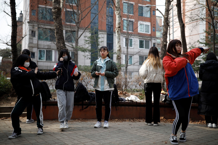 Japanese children warm up for an audition at a park. Young women are shown doing dance moves in an outdoor park.