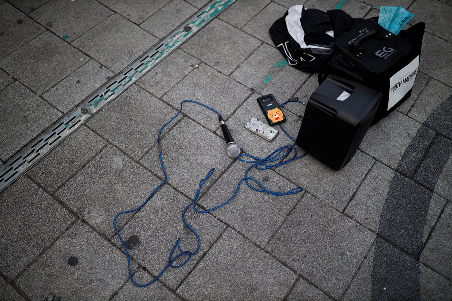 Microphone and speakers lie on the ground. A microphone is shown laying on the ground connected to a small amplifier.