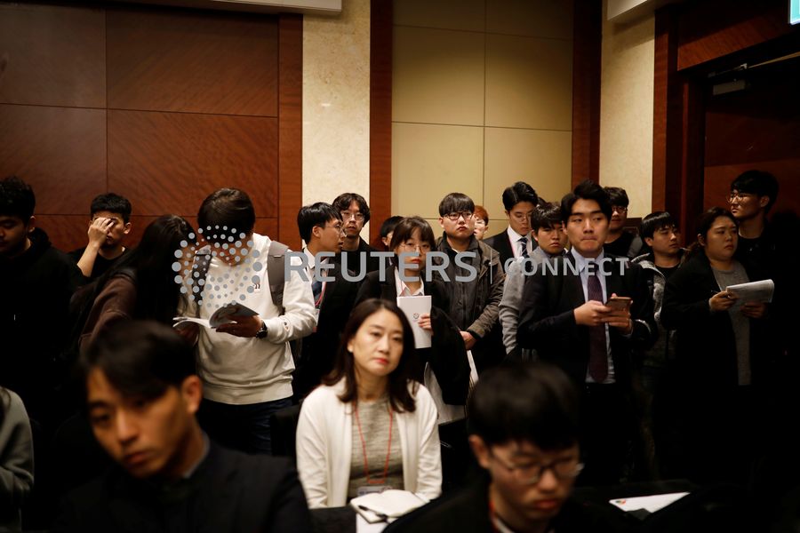 A group of forlorn-looking young people in business attire