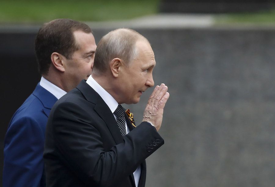 Russian President Vladimir Putin and Prime Minister Dmitry Medvedev arrive for the Victory Day parade in central Moscow, Russia, May 9, 2019. Russian President Vladimir Putin is shown waving with Prime Minister Dmitry Medvedev slightly behind him.