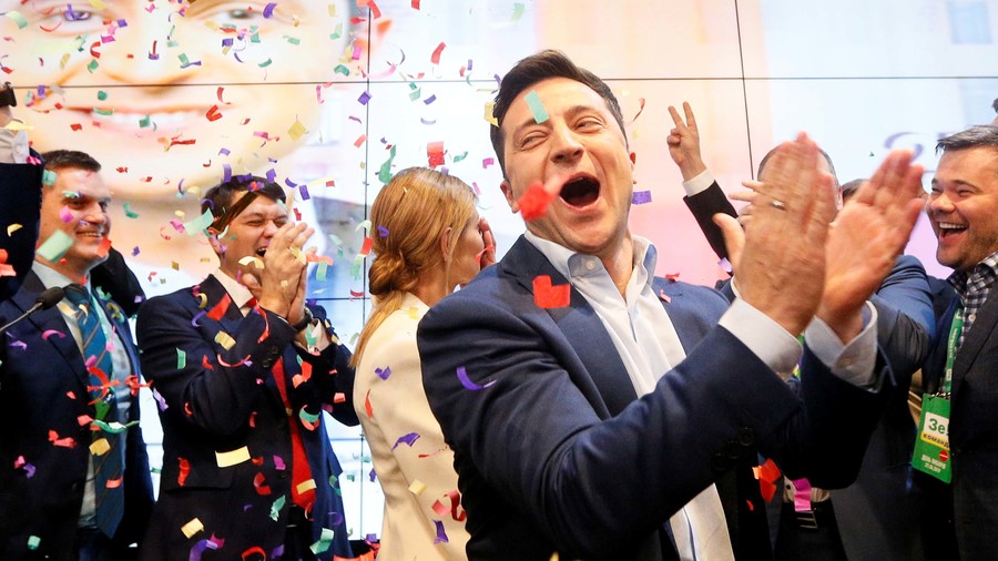 Volodymyr Zelenskiy A man claps in the foreground as confetti floats through the air