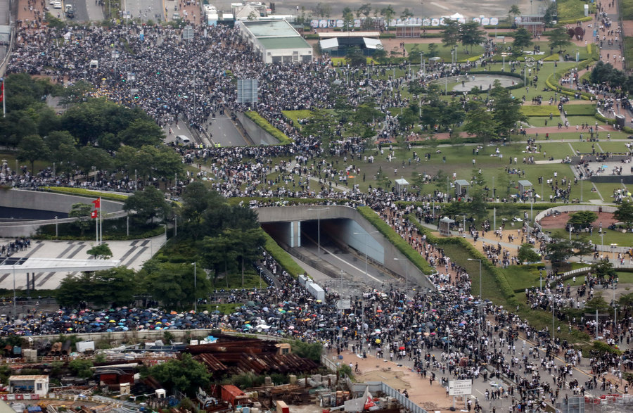 Protesters march along a road demonstrating against a proposed extradition bill in Hong Kong, China, June 12, 2019. Picture taken through a glass window. Thousands of demonstrators are shown crowding a main road in Hong Kong in a photo taking from several stories up through a window.