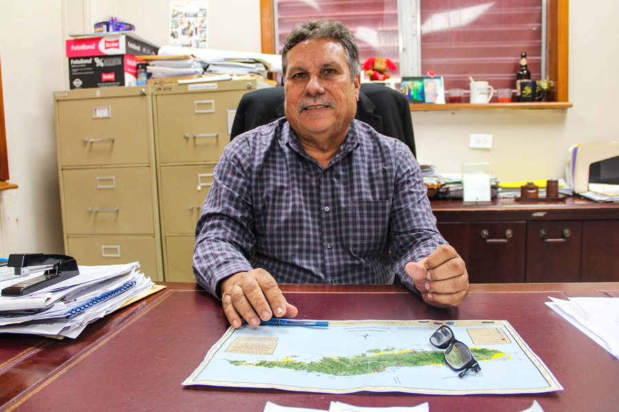 Vieques Mayor Victor Emric says he has little power over the terms of development and tourism on the small island. A man in a checkered, button down shirt is shown sitting at a desk with a map sitting on the surface.