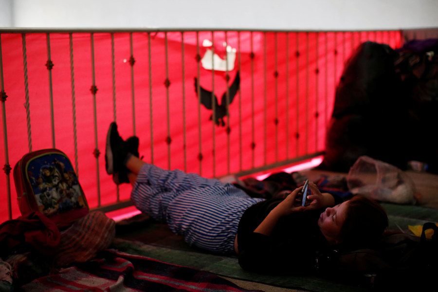 Cecilia Chirinos, a Honduran migrant, rests inside a shelter after she was sent by the Customs and Border Protection to Mexico from the US under the MPP. A woman is shown laying on her back and holding a photo to her face.