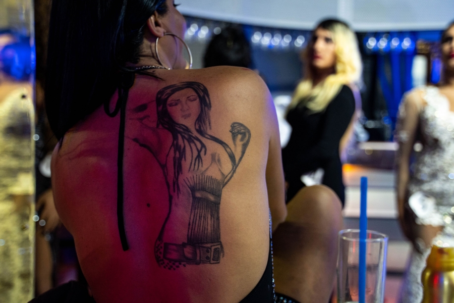 Gozde Bal shows off her tattoo of an idealized woman. A tatoo is shown on the back of a person in dark outline showing a woman with long hair and her arm raised.