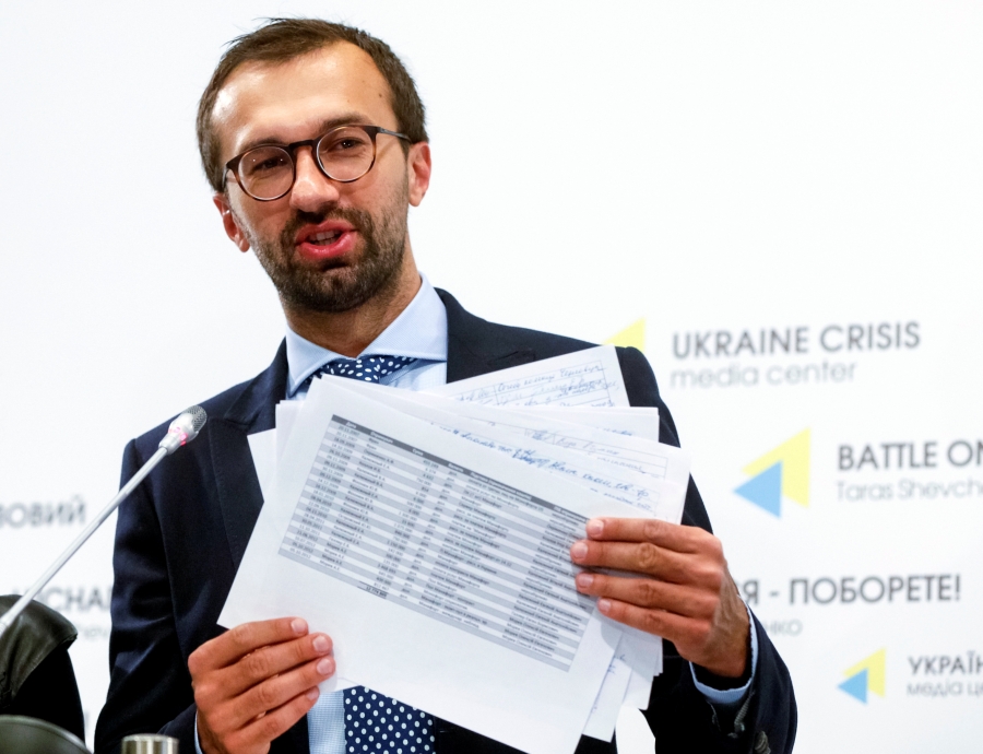 A man stands holding papers