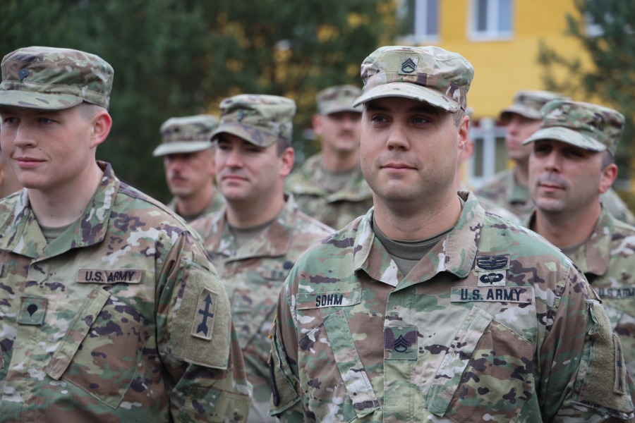 Sgt. Samuel Sohm with the Wisconsin National Guard focus on a mid-shot of a man in US Army uniform with others around him.