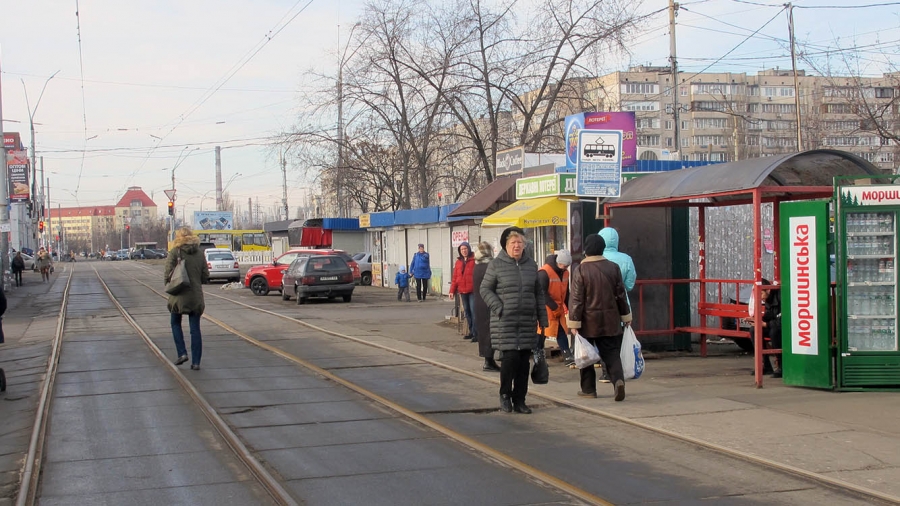 A tram line cuts through a suburban neighborhood in Kyiv, Ukraine. A tram line cuts through a suburban neighborhood in Kyiv, Ukraine, as people walk on the street.