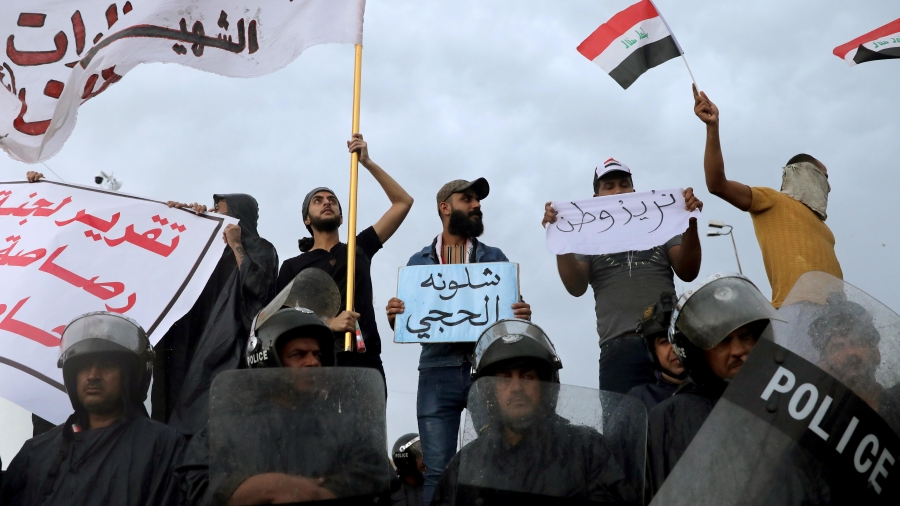 Iraqi policemen stand in front of demonstrators during a protest over corruption, lack of jobs, and poor services, in Kerbala, Iraq, on October 25, 2019. Iraqi policemen stand in front of demonstrators during a protest over corruption, lack of jobs, and poor services, in Kerbala, Iraq, on October 25, 2019.
