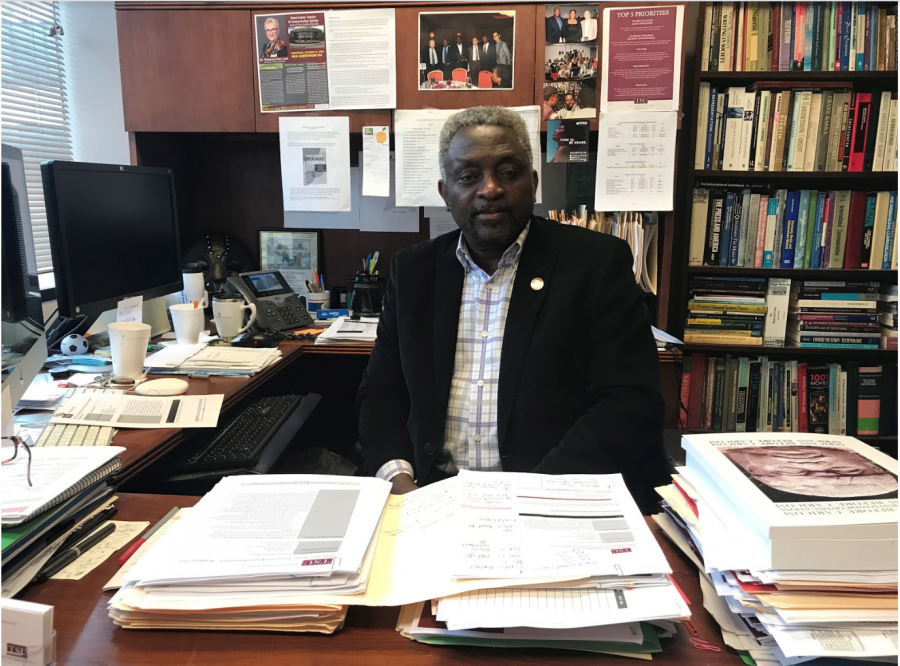 Texas Southern University media professor Dr. Chris Ulasi A man sits behind a desk with books and papers