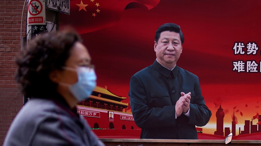 A woman wearing a protective mask is seen past a portrait of Chinese President Xi Jinping on a street as the country works to contain the coronavirus pandemic, in Shanghai, China. A woman is shown in soft focus and wearing a protective mask while walking past a portrait of Chinese President Xi Jinping on a red background.