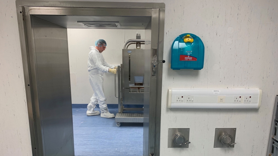 A scientist at Cobra Biologics works on an initiaitve for a potential vaccine for COVID-19 in Keele, Britain, April 30, 2020. A scientist is shown through a doorway wearing protective medical clothing while working at a machine.