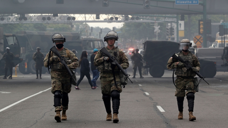 US National Guard members walk at the area in the aftermath of a protest in Minneapolis, Minnesota, May 29, 2020 Several US National Guard members are shown wearing military fatigues and carrying weapons while walking in a street.
