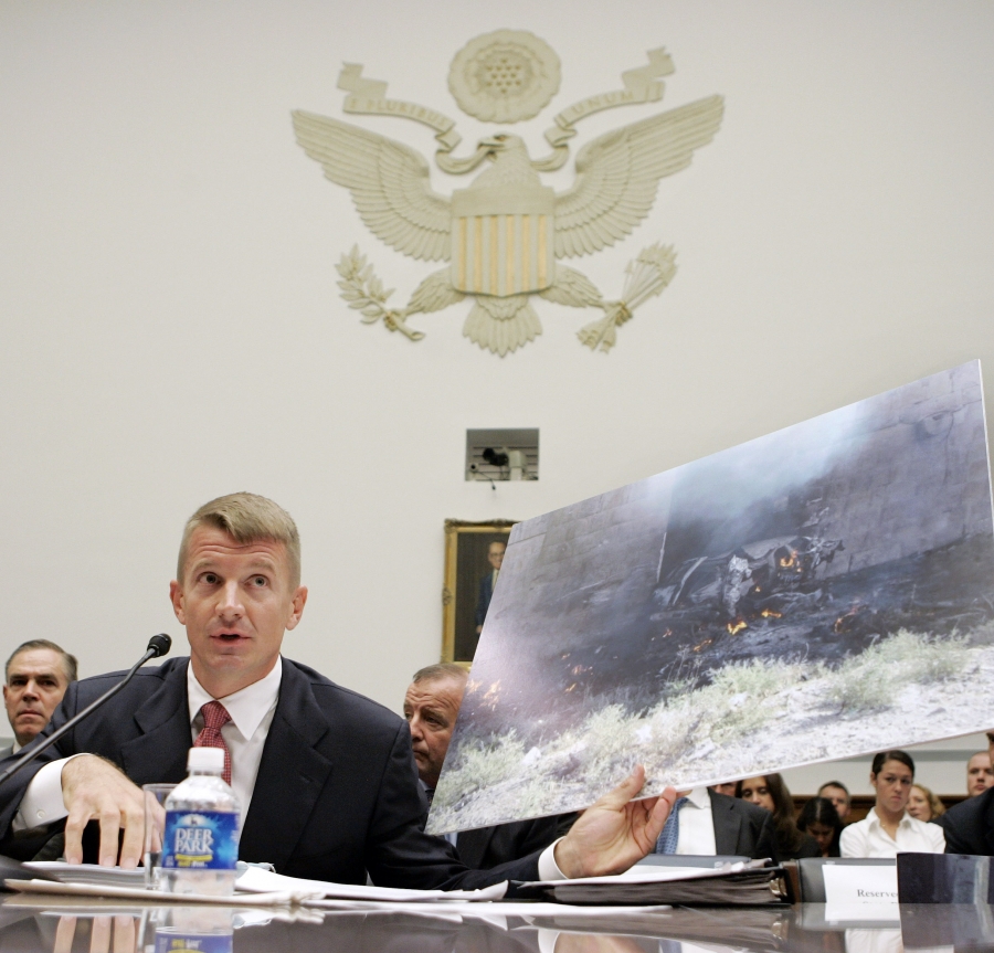 Blackwater Chief Executive Erik Prince A man sits at a desk in front of an emblem of the United States, holding a large photograph