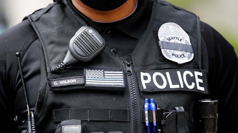 A Seattle police officer wears a "mourning band" for fallen officers over his badge, obscuring the badge number, as Seattle police guard the department headquarters downtown during a rally and march calling for a defunding of Seattle police, in Seattle. A Seattle police officer wears a "mourning band" for fallen officers over his badge, obscuring the badge number, as Seattle police guard the department headquarters downtown during a rally and march calling for a defunding of Seattle police, in Seattle, W