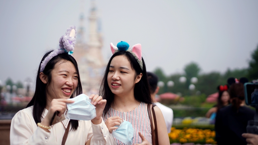 Visitors hold face masks at the Shanghai Disneyland theme park as it reopens following a shutdown due to the coronavirus disease (COVID-19) outbreak, at Shanghai Disney Resort in Shanghai, China May 11, 2020. Two young women with headbands hold face masks at the Shanghai Disneyland theme park as it reopens following a shutdown due to the coronavirus disease